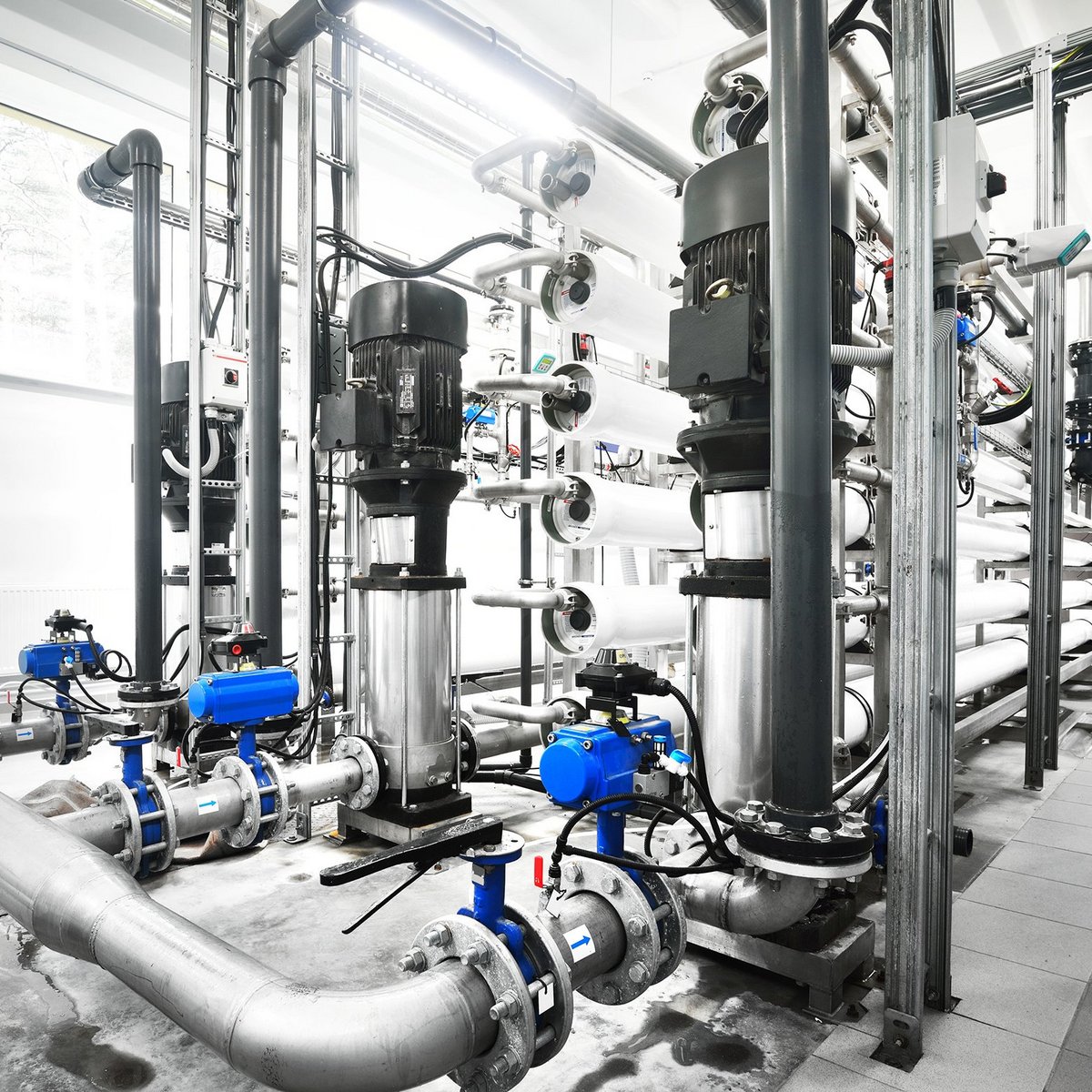 Eine moderne Wasseraufbereitungsanlage mit zahlreichen Rohren und Pumpen, die in einem hellen Raum angeordnet sind.